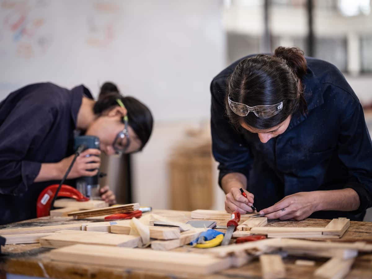 Estudiantes de la Universidad Anáhuac trabajando con madera y herramientas de carpintería, mostrando destreza en el uso de equipos para proyectos prácticos.